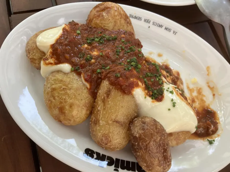 Patates braves amb allioli en un plat d'Amicks