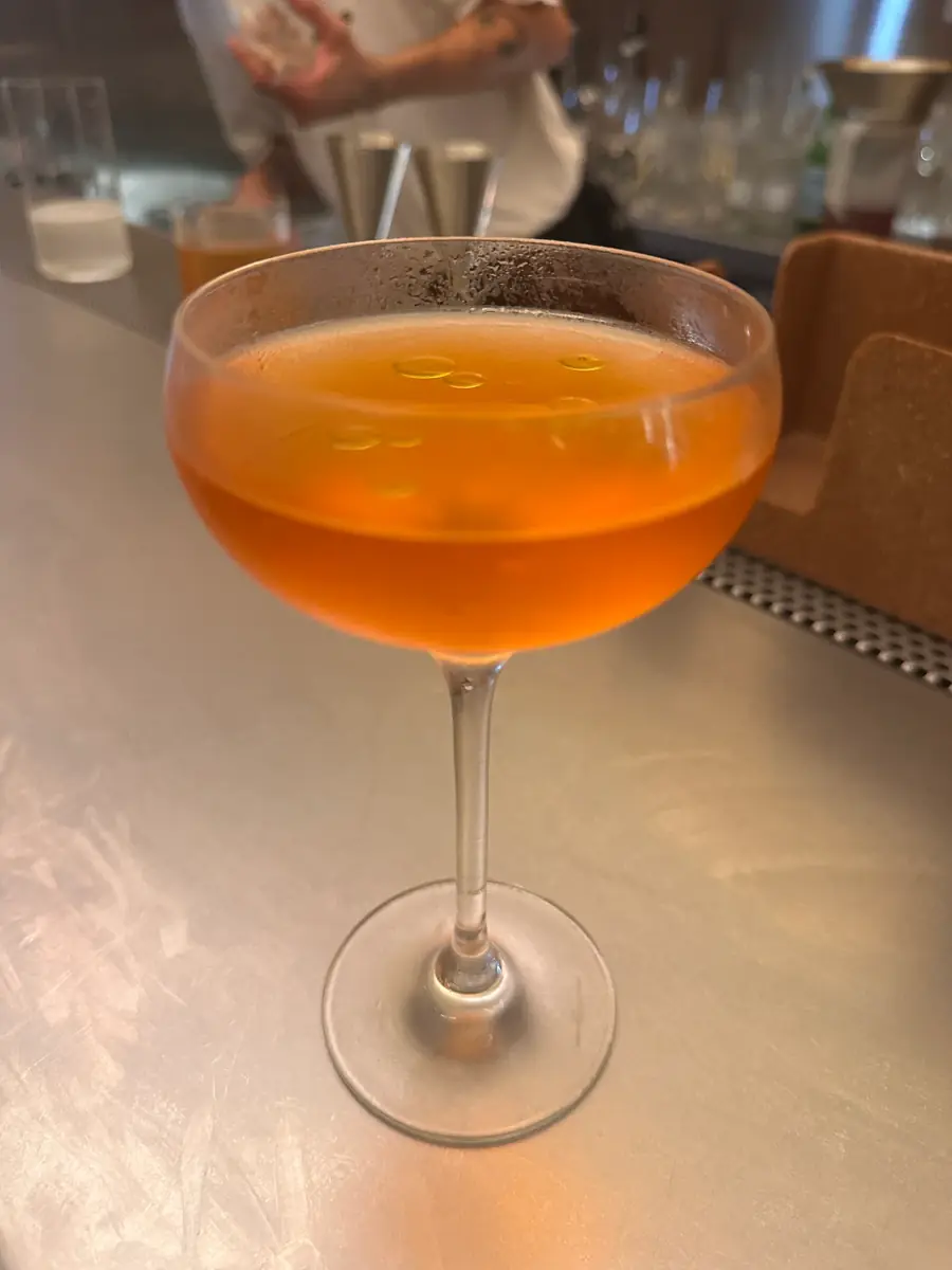Un còctel de color ambre en copa, sobre la barra