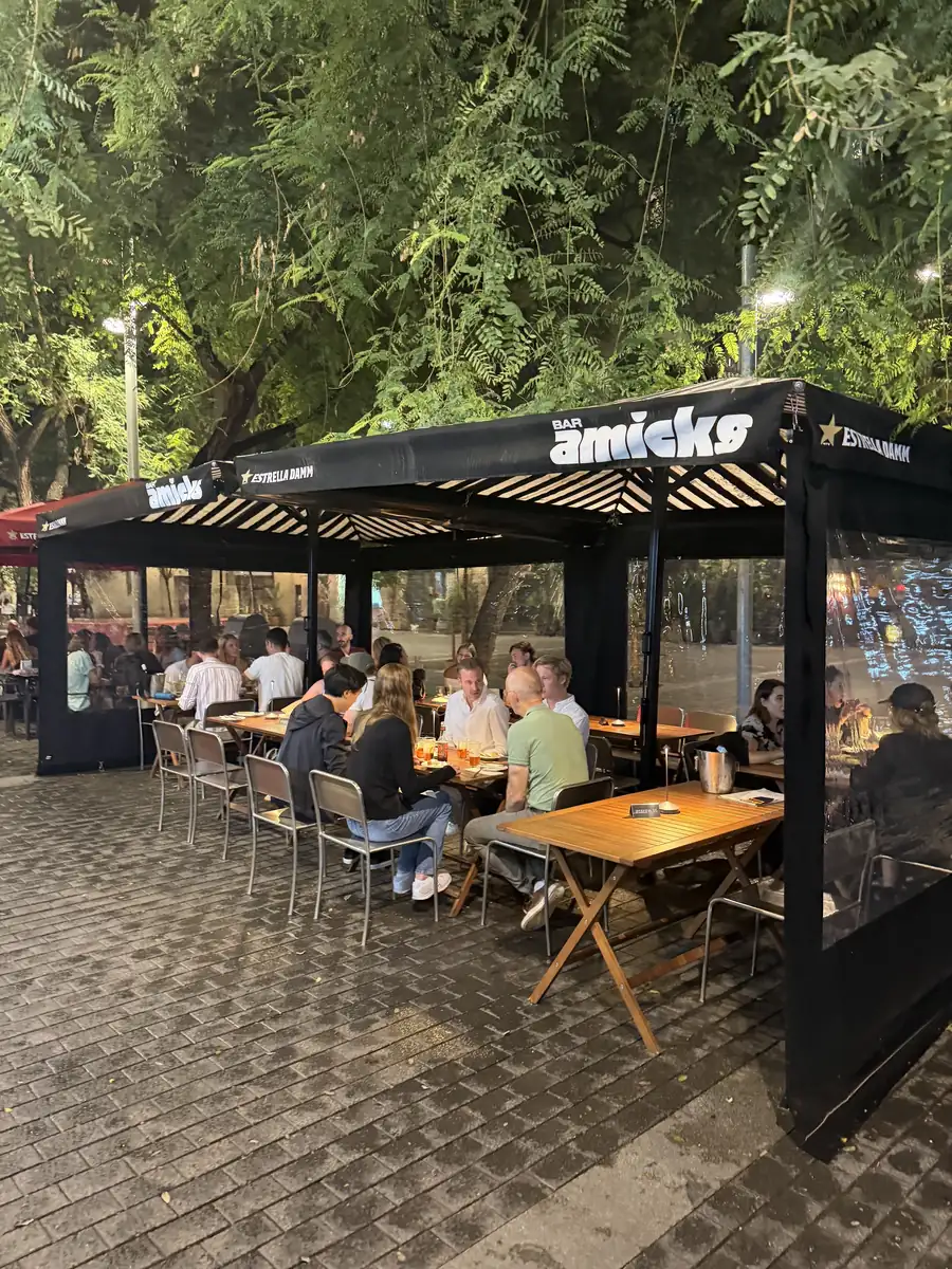 La terrassa del Bar Amicks de nit, plena, sota el seu tendal