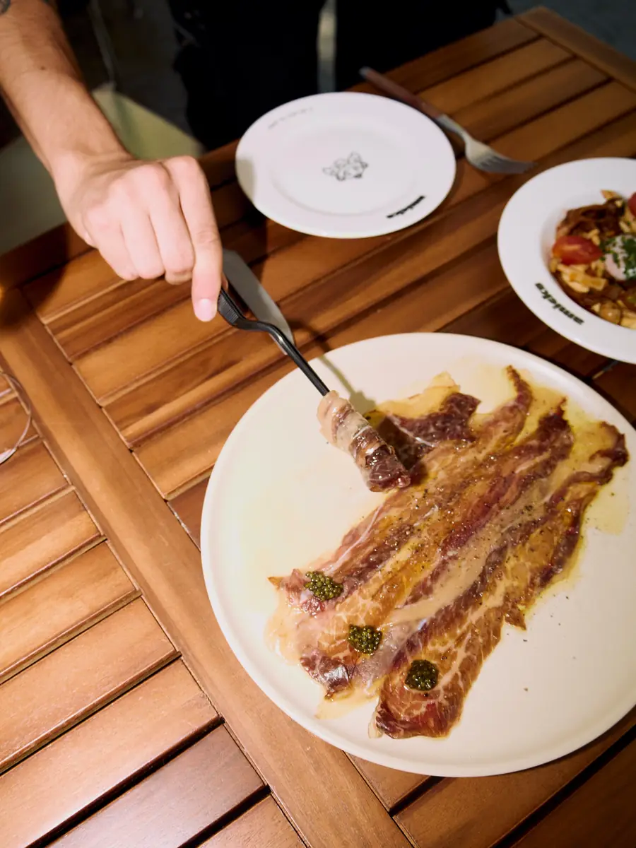 Picanya a la brasa tallada a làmines; un comensal se serveix amb la forquilla