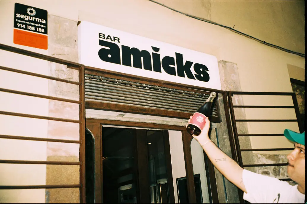 Un cambrer penja una ampolla al costat del rètol del Bar Amicks