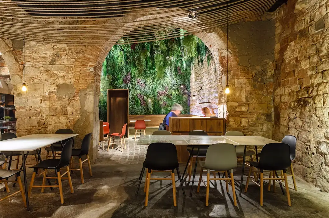 La taula llarga del menjador, sota l’arc i la paret de vegetació