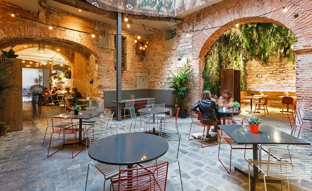 La terrassa interior de La Bona Sort, amb taules i plantes sota els arcs de pedra