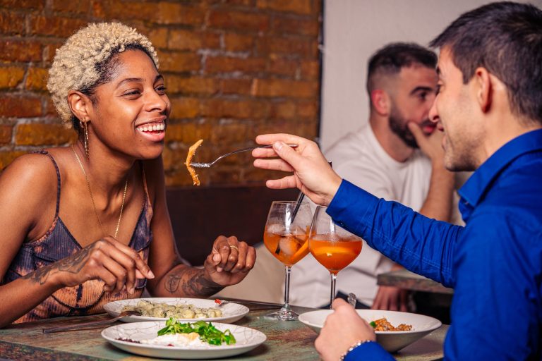 Una pareja compartiendo pasta y risas en el comedor