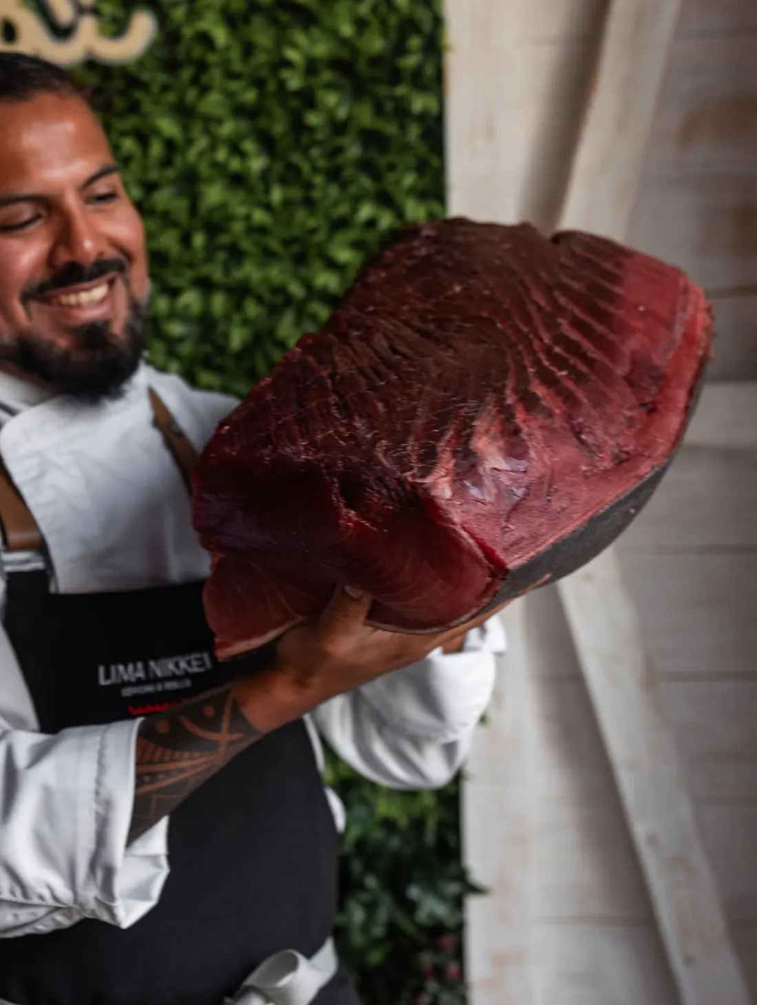 Un cocinero de Lima Nikkei sonríe con un lomo de atún rojo entero en las manos