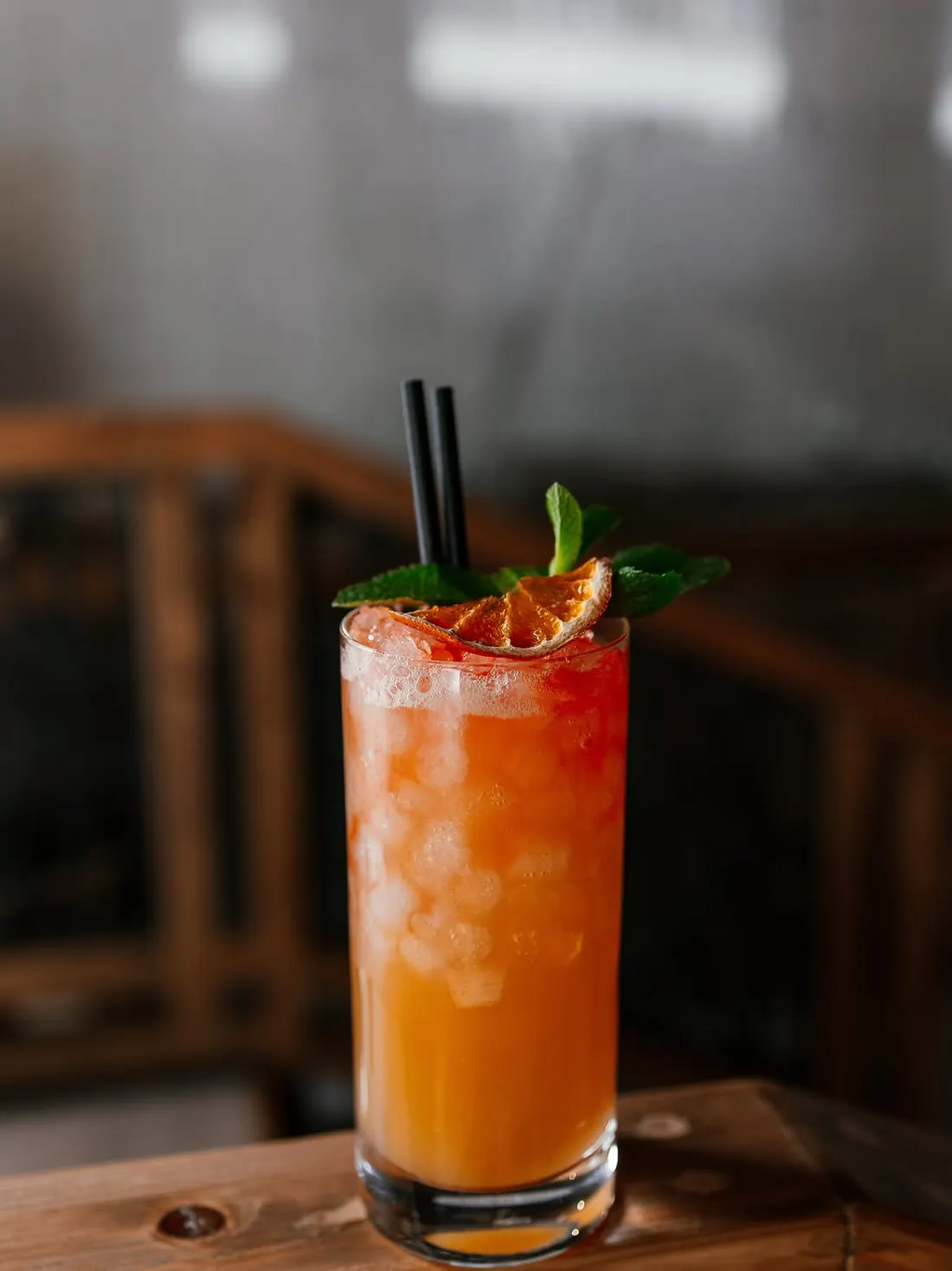Cóctel naranja con hielo y hierbabuena en vaso alto