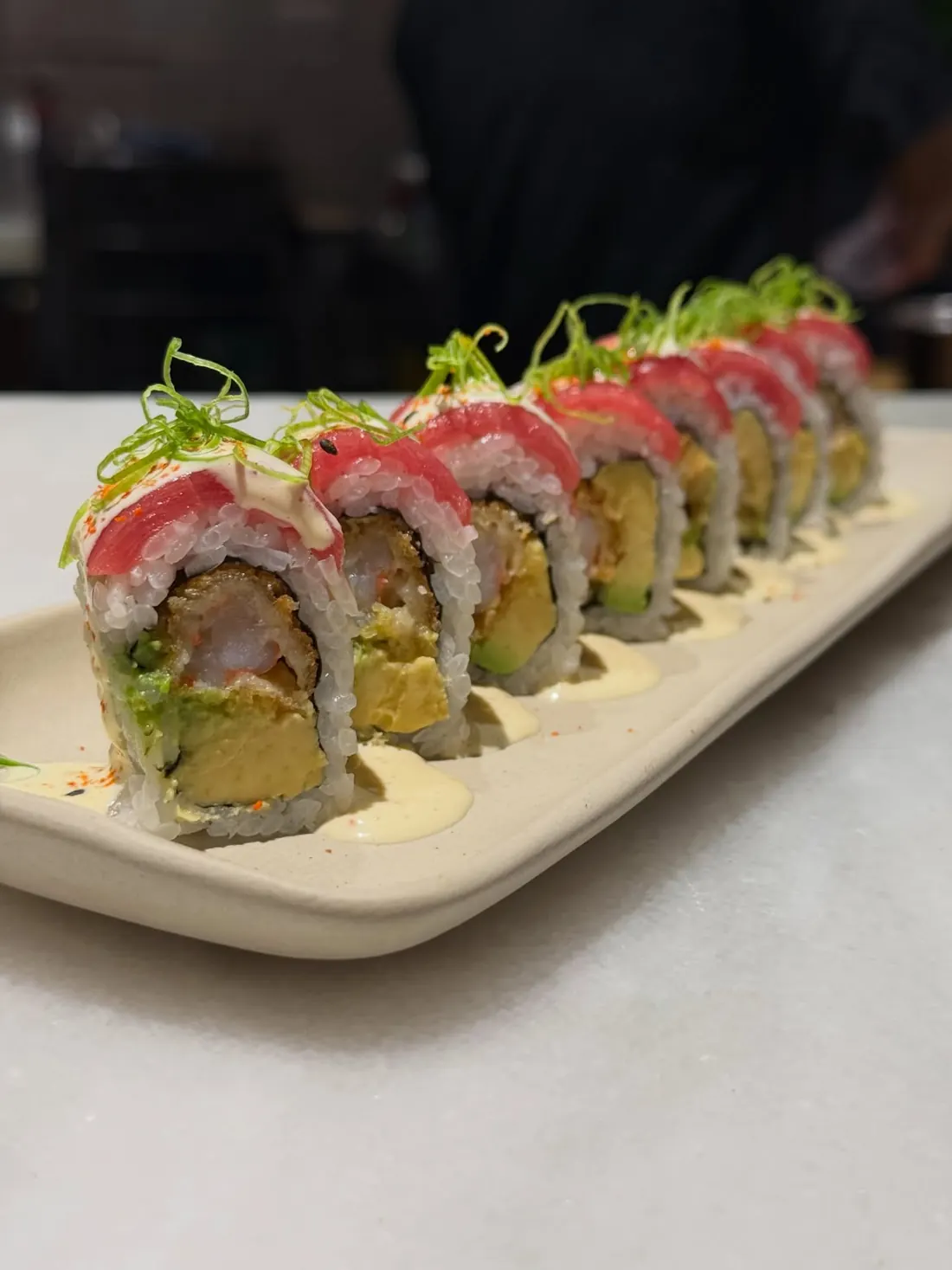 Hilera de makis cubiertos de atún con brotes verdes