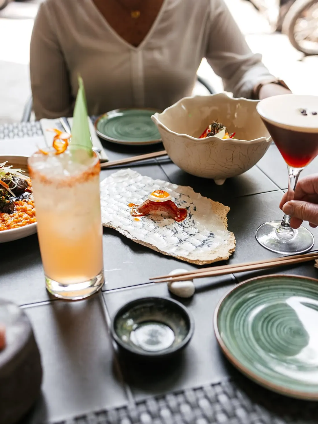 Una clienta en la mesa con cócteles y platos para compartir