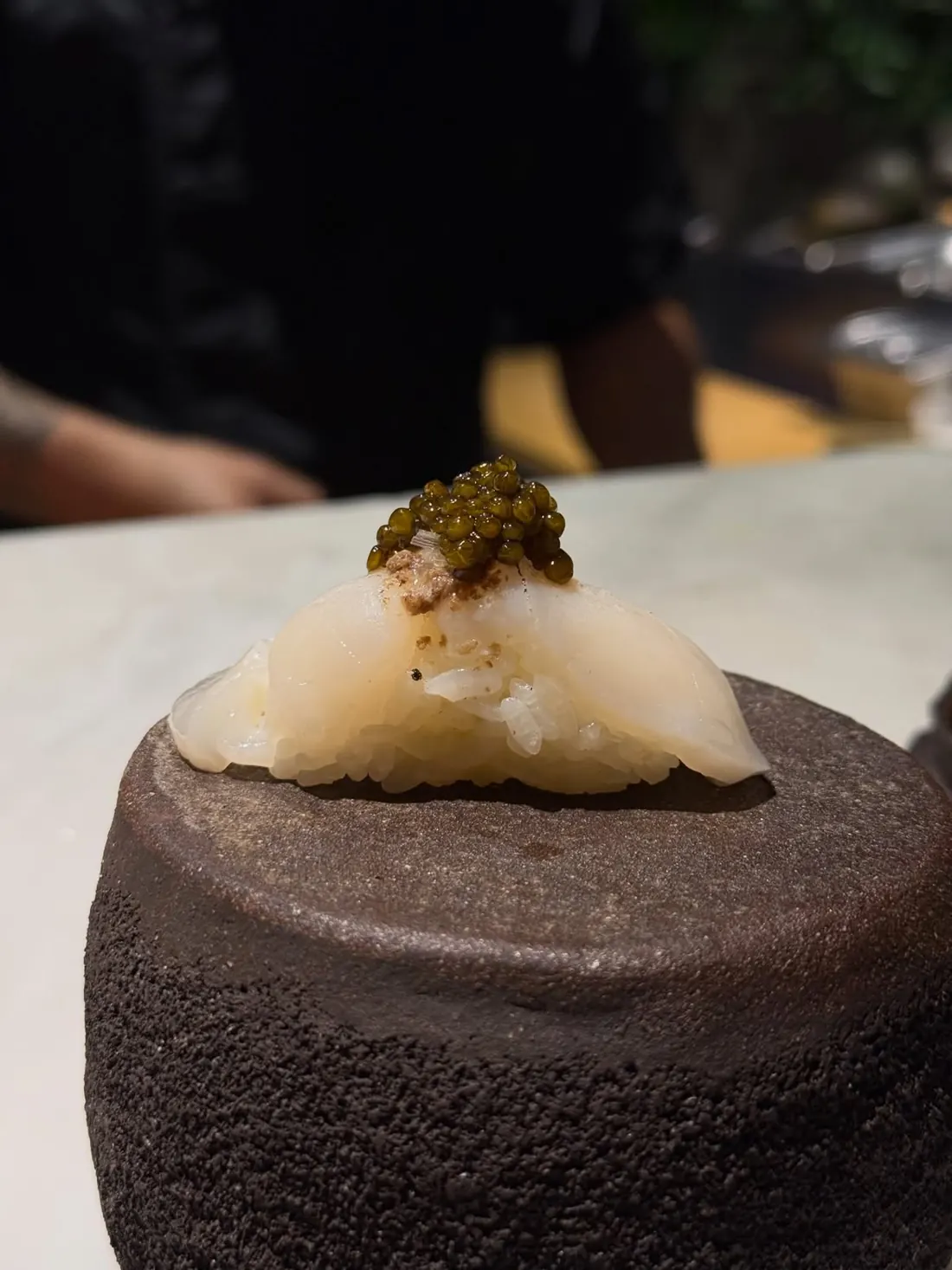 Nigiri de vieira con caviar sobre piedra volcánica