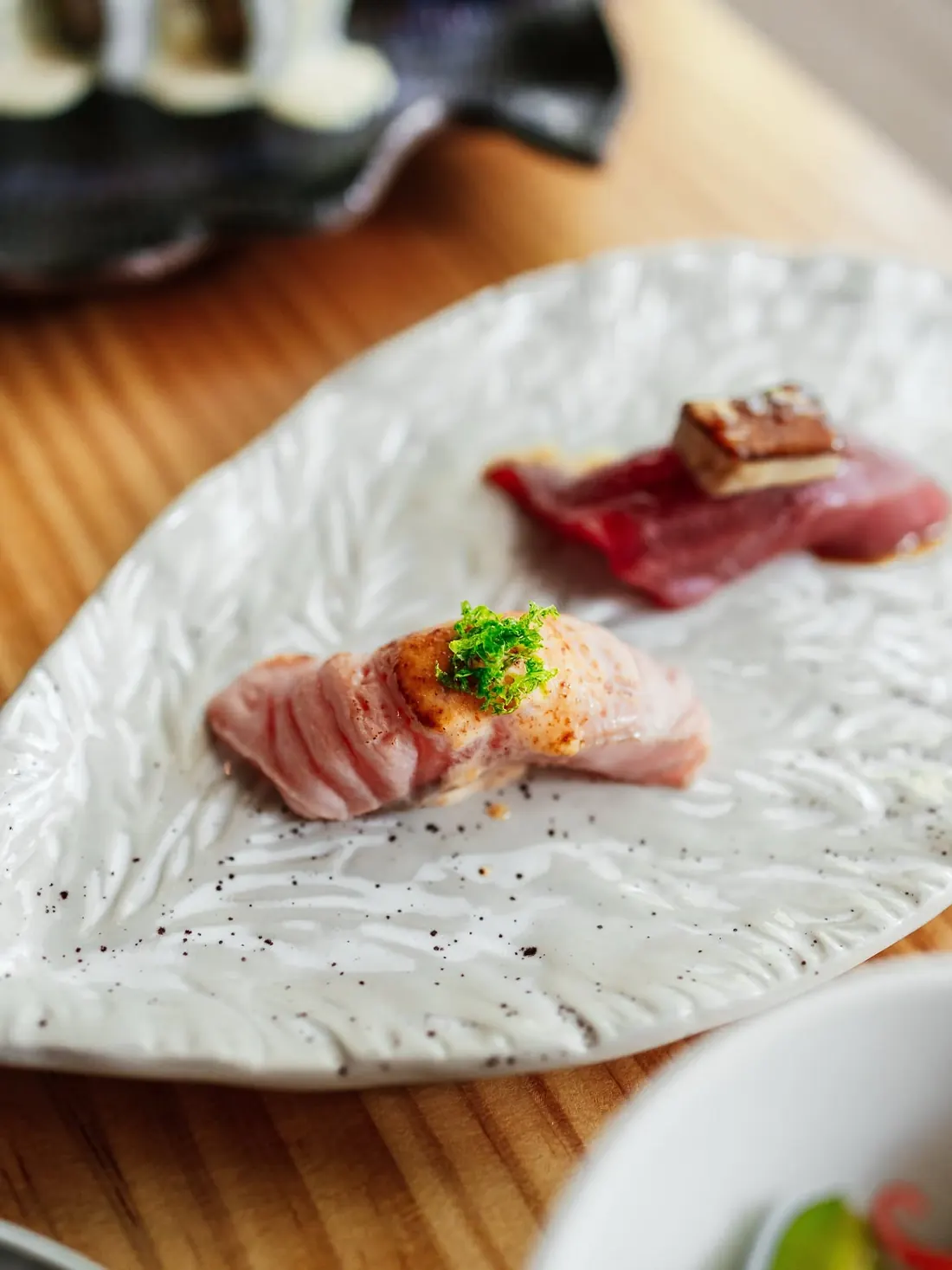 Nigiris de atún y pescado blanco sobre un plato de cerámica blanca