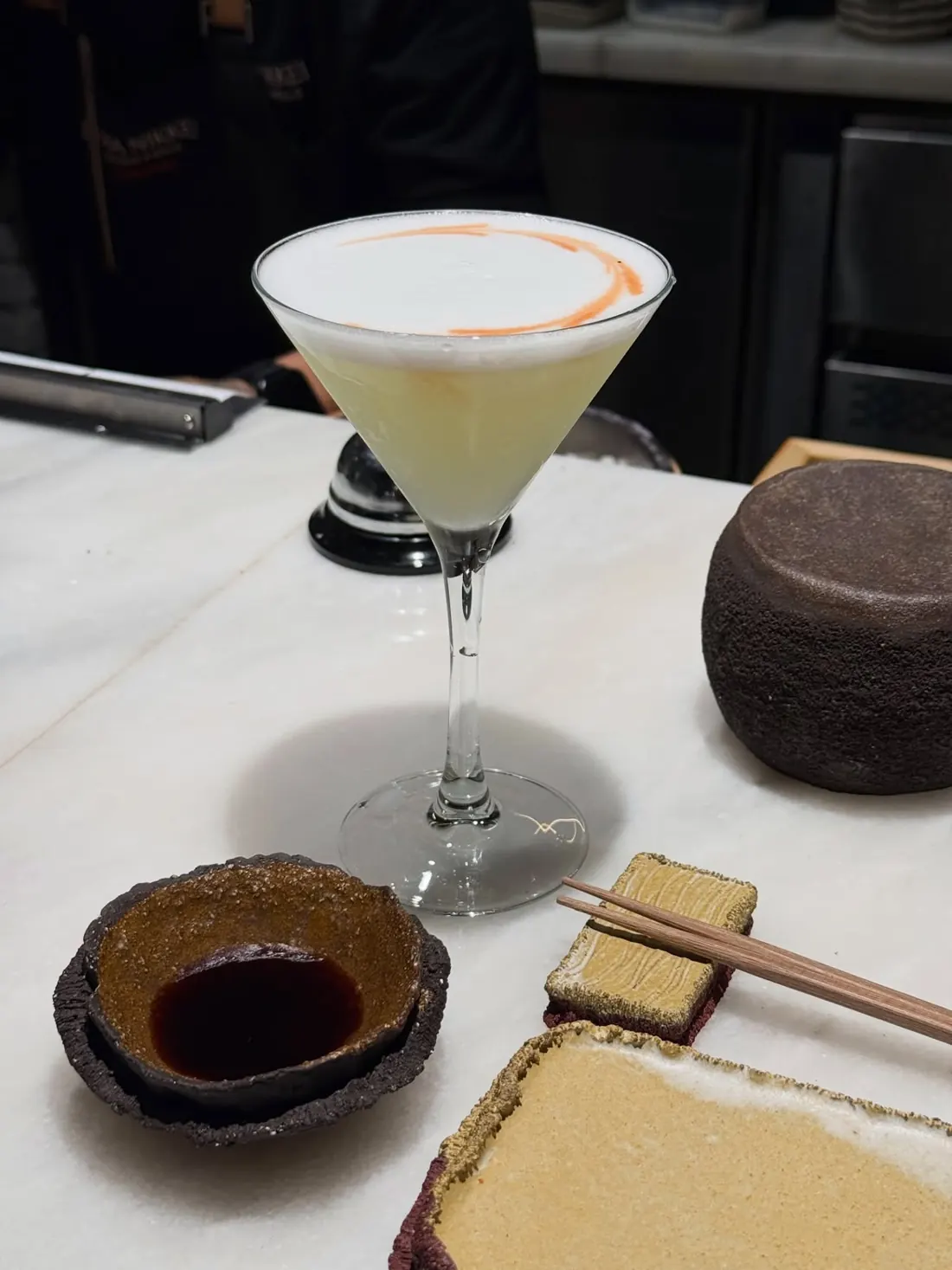 Un pisco sour en copa de cóctel sobre la barra de mármol