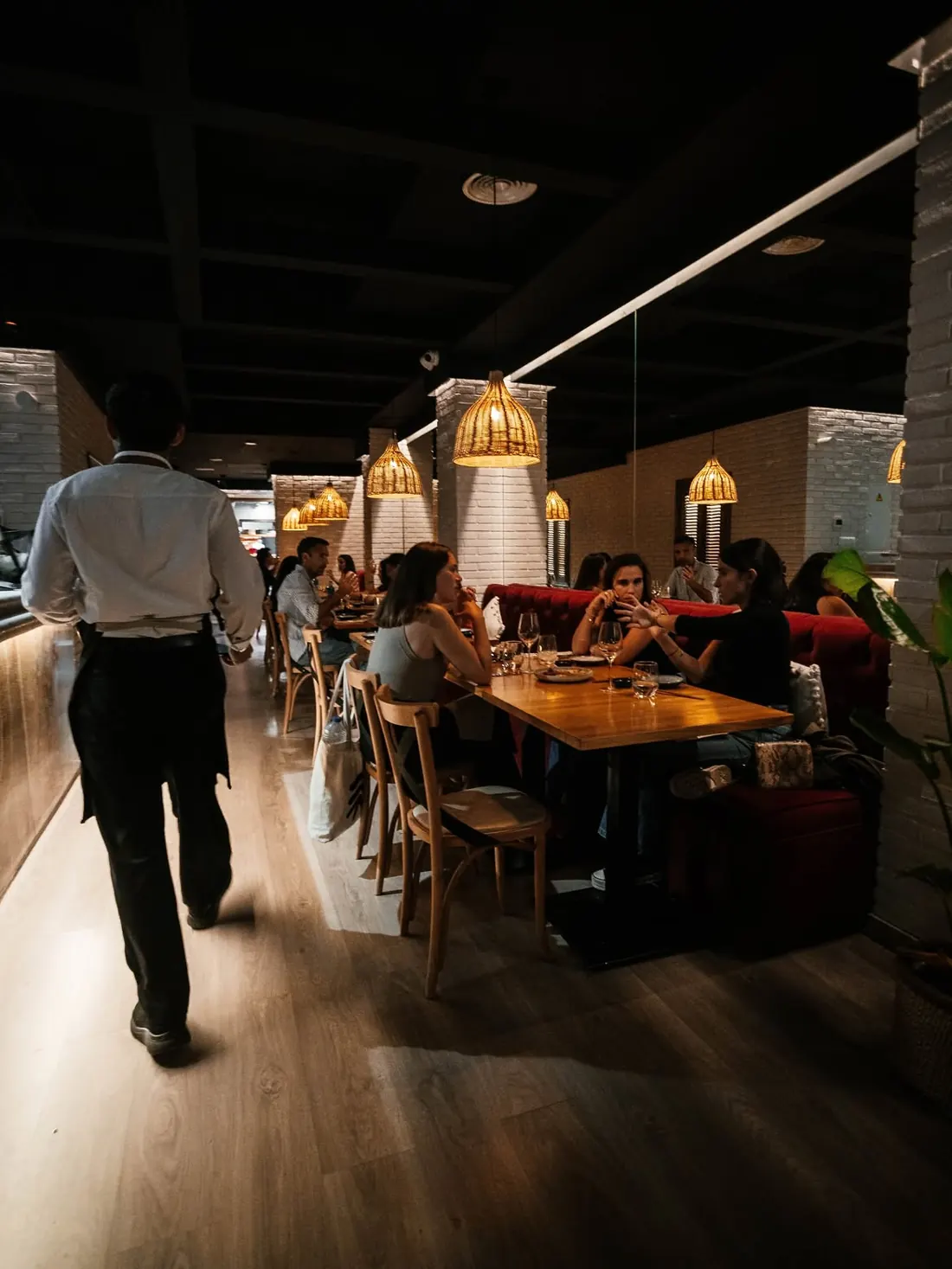 La sala de Lima Nikkei de noche, con un camarero pasando entre las mesas ocupadas
