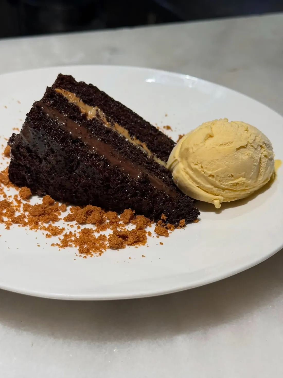 Tarta de chocolate en capas con una bola de helado y crumble