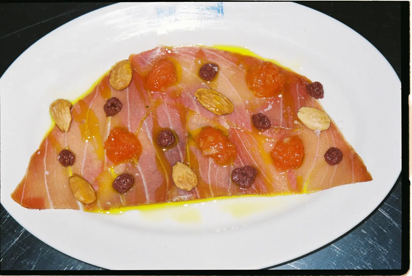 Carpaccio de atún con olivada, tomate confitado y almendras