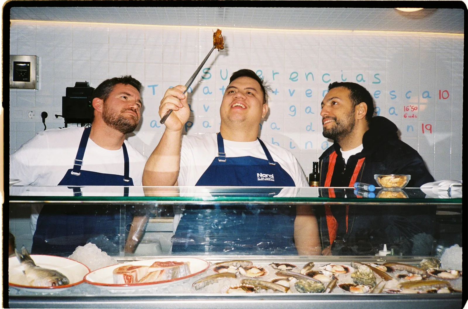 Los tres cocineros de Nardi entre bromas, detrás de la vitrina del marisco