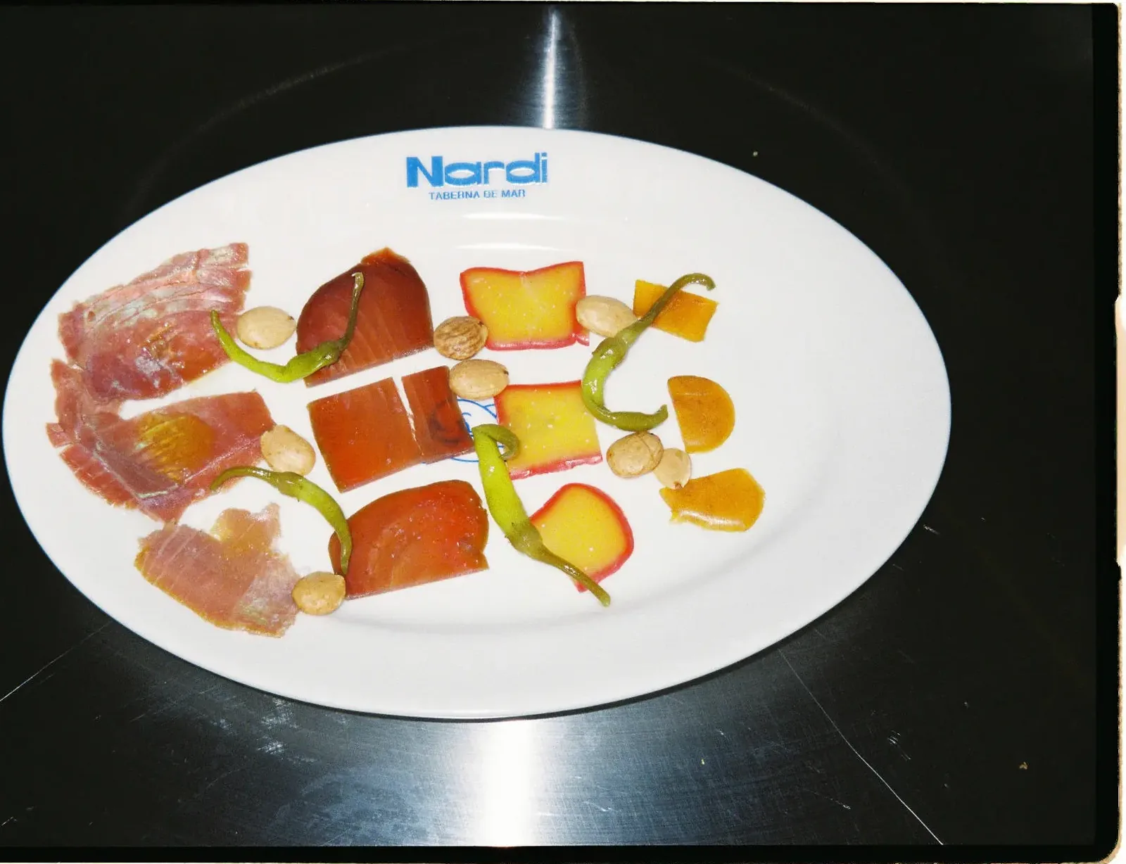 Crudos de pescado con encurtidos y frutas, en plato con el logo de Nardi