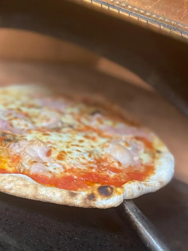 Una pizza entra en el horno de cobre de Via Napoli
