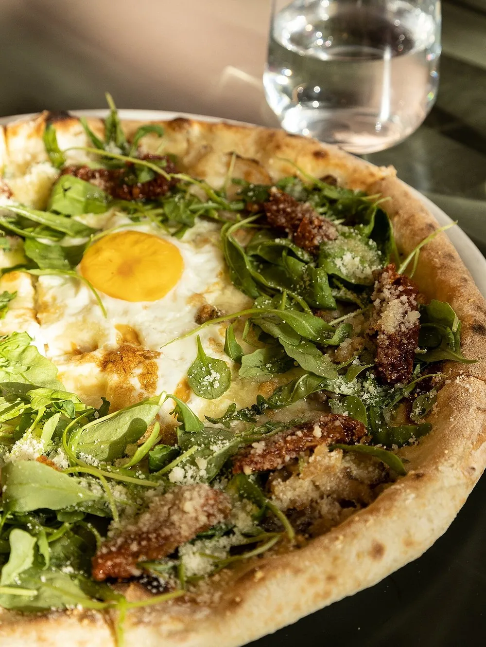 Pizza blanca con huevo, rúcula y tomate seco